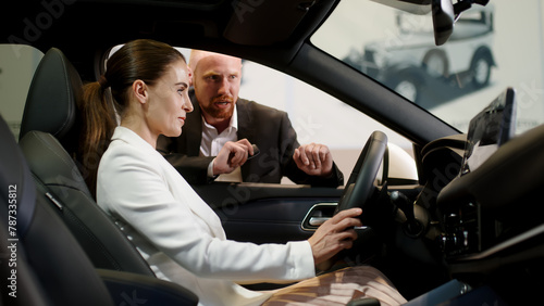 An interested buyer consults with a car dealership manager about the models and characteristics of a modern electric car. Concept of buying and selling a car, deal.