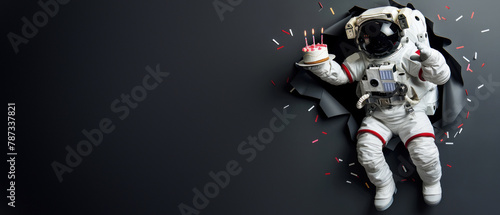 A weightless astronaut holds a birthday cake with candles, set against a monochromatic background photo