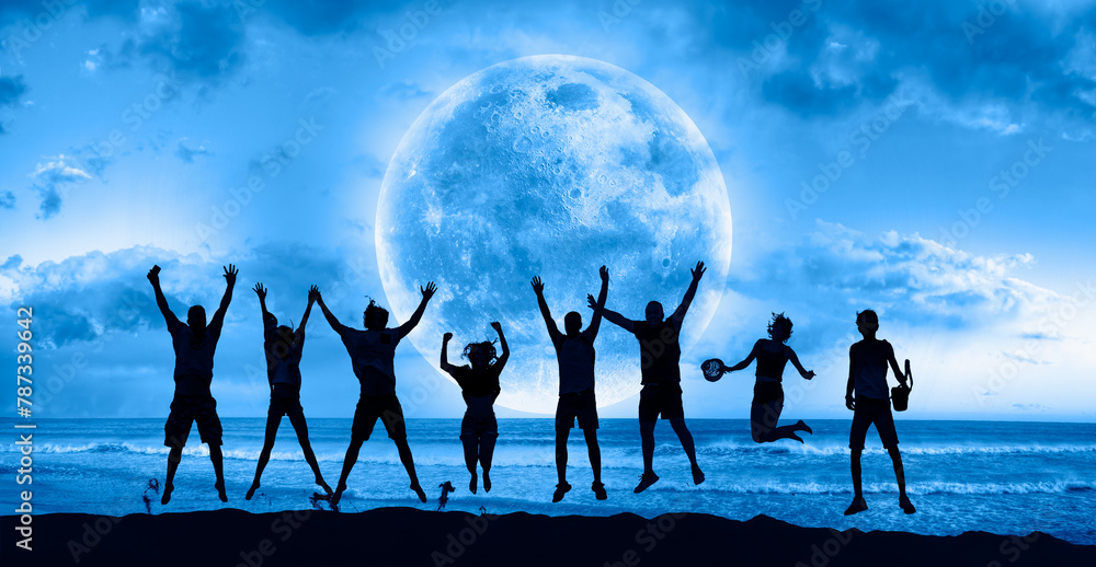 Obraz premium A group of young people jumping under the moonlight by the sea 