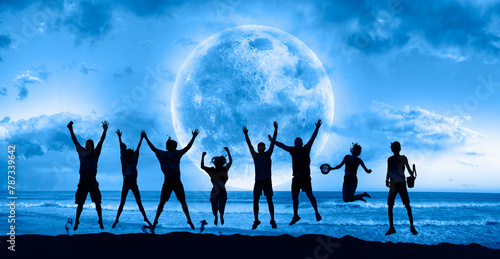 A group of young people jumping under the moonlight by the sea  "Elements of this image furnished by NASA"