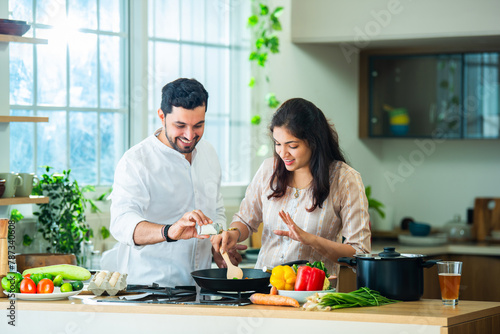 Indian couple in kitchen - Young Beautiful asian wife enjoying cooking with husband.