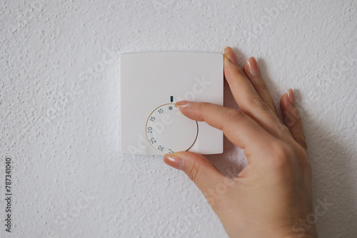 Human hand turns off the heating at home. Central Heating thermostat control dial adjustment