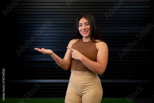Young woman in sportswear points at a space for advertising text