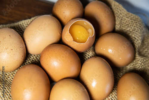 close-up of raw eggs on burlap, one egg is broken and the yolk is visible