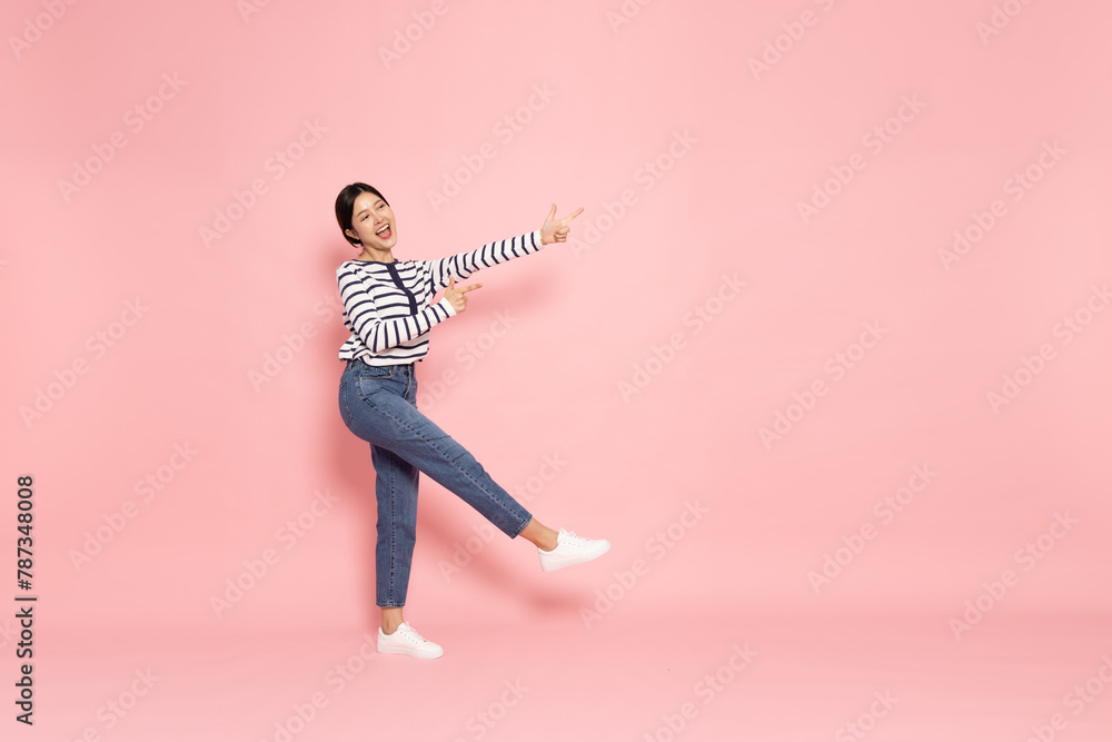 Young beautiful Asian woman pointing to empty copy space isolated on pink background