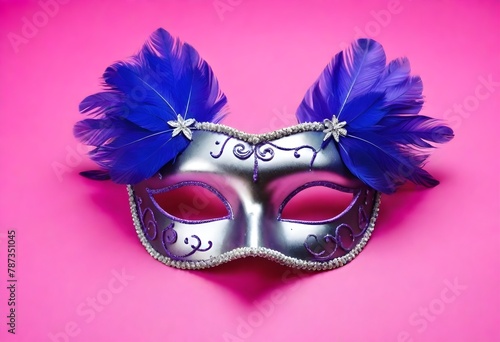 A purple feathered masquerade mask with silver glitter and ribbons on a pink background