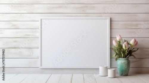 A mock-up of an empty wooden picture frame on a light wall background. A vase with flowers and leaves. The concept of advertising, a place for text. © Cherkasova Alie
