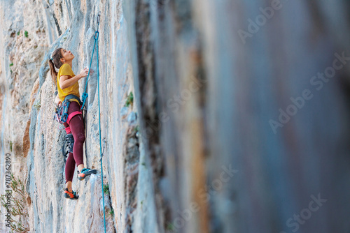 Climber overcomes challenging climbing route. A girl climbs a rock. Woman engaged in extreme sport. .