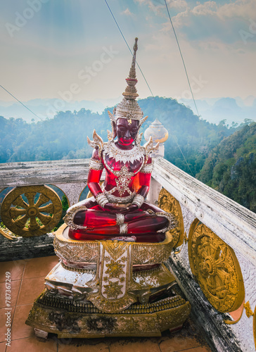 Red glass Meditation Buddha statue ornate with golden jewels at the hilltop pagoda of the Wat Tham Sua aka Tiger Cave Temple of Krabi Thailand photo