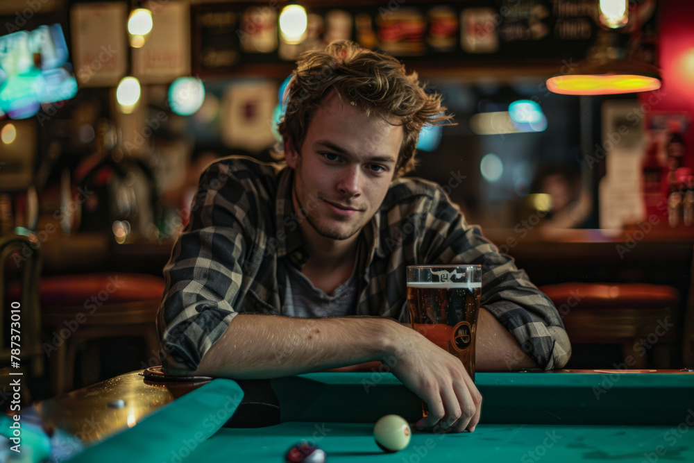A young Caucasian man enjoys a beer beside a billiard table in a pub setting