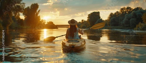 Young woman kayaking in calm river at sunset, outdoor travel adventure concept