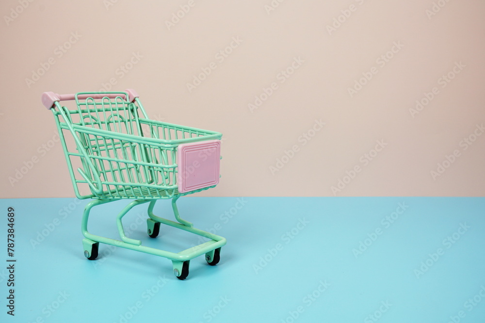 Mini Trolley shopping cart with space for text on pink and blue background