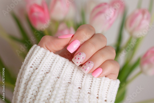Beautiful female hands with pink manicure nails, flower design
