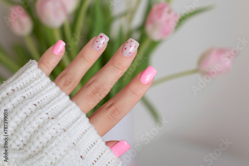 Beautiful female hands with pink manicure nails, flower design