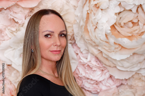 
Middle aged woman with long straight ombre blonde hair on flower wall background
