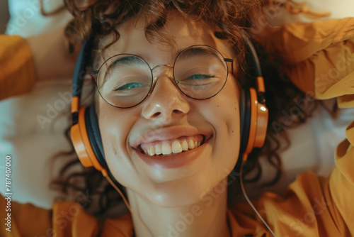 Joyful young female with headphones capturing herself on video or photos. Adolescent in her space, celebrating a victory, immersed in music, or engaging in a creative pastime, illustrating indoor acti photo