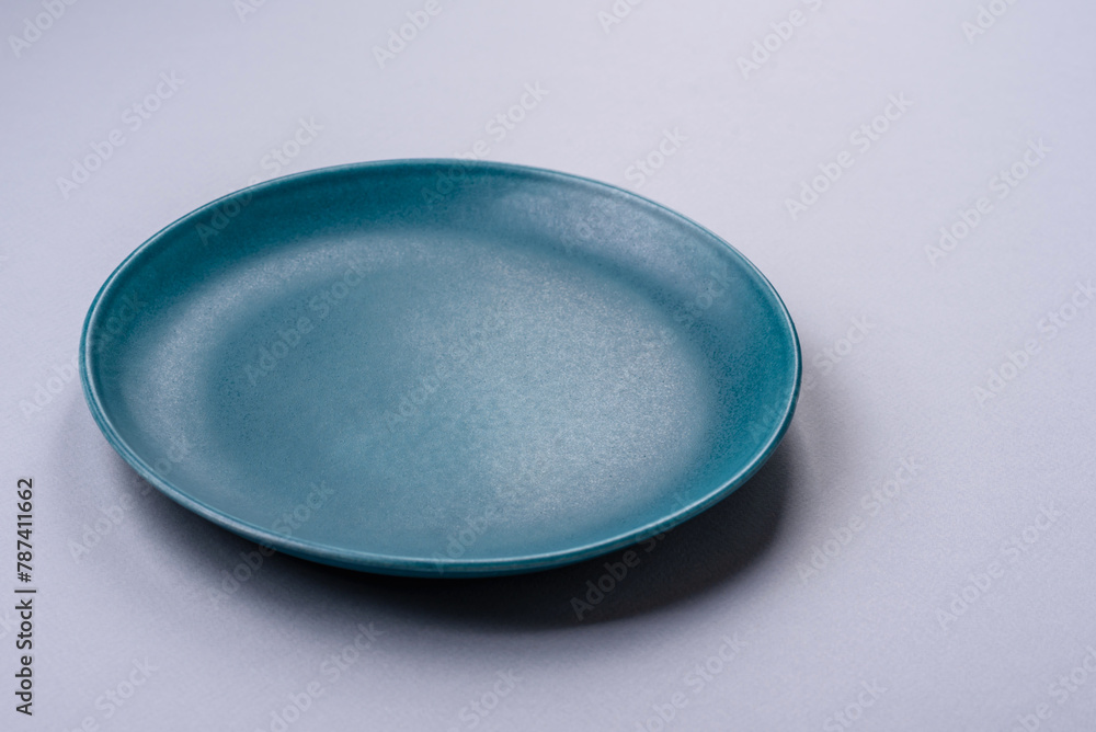 An empty plate on a gray concrete background with copy space - obrazy, fototapety, plakaty 