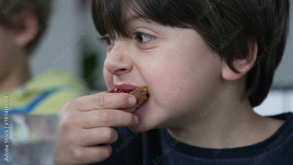 Close-up face of small boy eating bread with jelly for breakfast, candid kid snacking carb food Close-up face of small boy eating bread with jelly for breakfast, candid kid snacking carb food