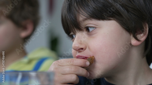Close-up face of small boy eating bread with jelly for breakfast, candid kid snacking carb food photo
