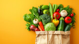 A bag of vegetables is displayed on a yellow background. The vegetables include broccoli, carrots, tomatoes, and peppers. The bag is brown and he is full, suggesting that it is a grocery bag.