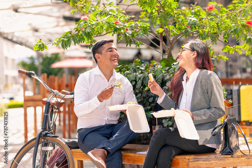 Friends talk happily while lunch in a public place in the city. photo