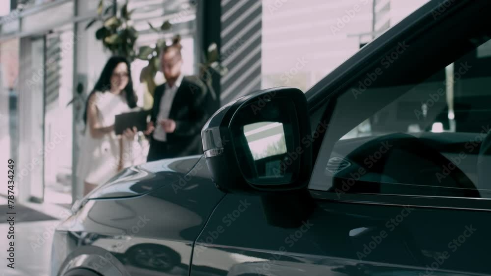 Close-up of the completion of a deal to purchase a new car at a car dealership. The car dealer and the buyer who bought the car. The manager hands over the key to the new owner at the car dealership. Close-up of the completion of a deal to purchase a new car at a car dealership. The car dealer and the buyer who bought the car. The manager hands over the key to the new owner at the car dealership.
