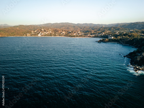 View of Sayulita Mexico looking east. Aerial view at sunset with waves crashing at point.