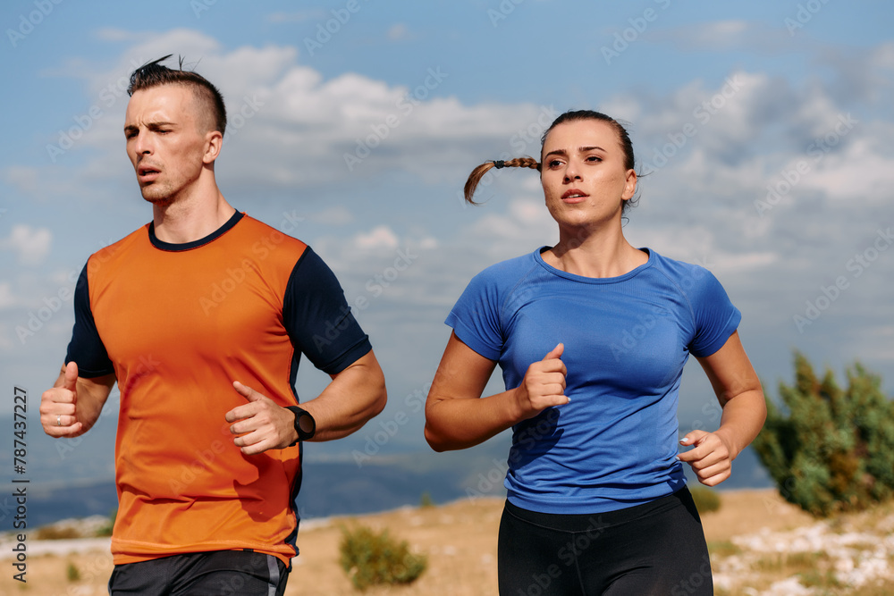 A couple dressed in sportswear runs along a scenic road during an early morning workout, enjoying the fresh air and maintaining a healthy lifestyle A couple dressed in sportswear runs along a scenic road during an early morning workout, enjoying the fresh air and maintaining a healthy lifestyle
