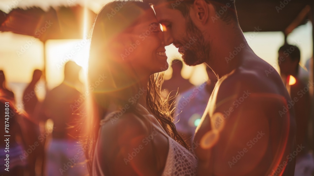 An intimate moment captured on a beach with a couple kissing as the sun ...