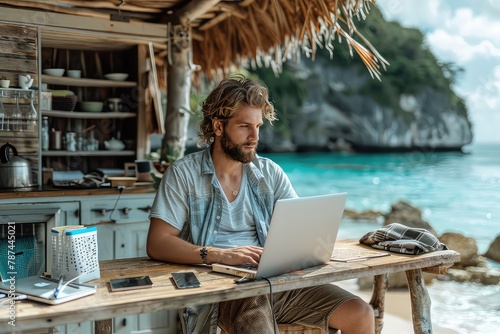 Male freelancer with laptop on the beach during sunset. Place of work of a hermit freelancer. The laptop on the beach table becomes a portal to the male freelancer's dreams.