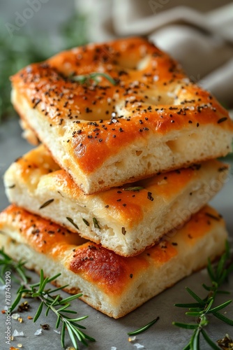 Stack of freshly baked focaccia with sesame and herbs on a grey background