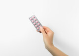 hand holding blister with pink pills on white background