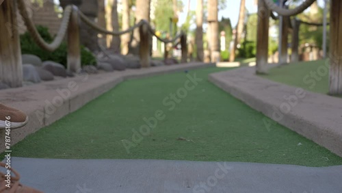This video shows a POV, ground level view of a miniature golf ball being hit by a golf club.