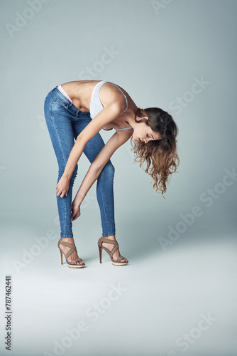 Woman, jeans and studio fitting for fashion clothing on grey background for denim pants, mockup space or style. Female person, model and heels or legs with outfit for size, dressing or getting ready