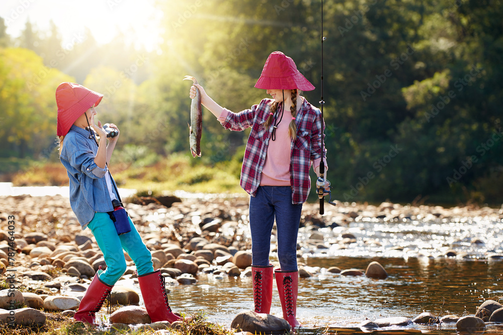 Countryside, binocular and fish with girls in river on holiday break, vacation or adventure as hobby. Sunshine, happy children or siblings and fishing rod on weekend trip, outdoor and nature to bond