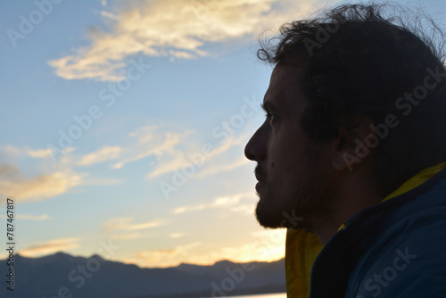 half portrait male man with brown hair, looking at the sky in backlight
