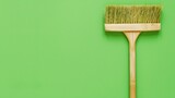 A single cleaning broom positioned against a vibrant green background, emphasizing simplicity and cleanliness