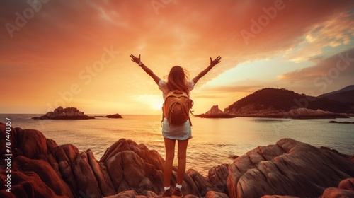 Happy woman raising arms up enjoying sunset on the beach - Delightful traveler standing with hands up looking morning sunrise - Self care, traveling, wellness and healthy life style concept photo