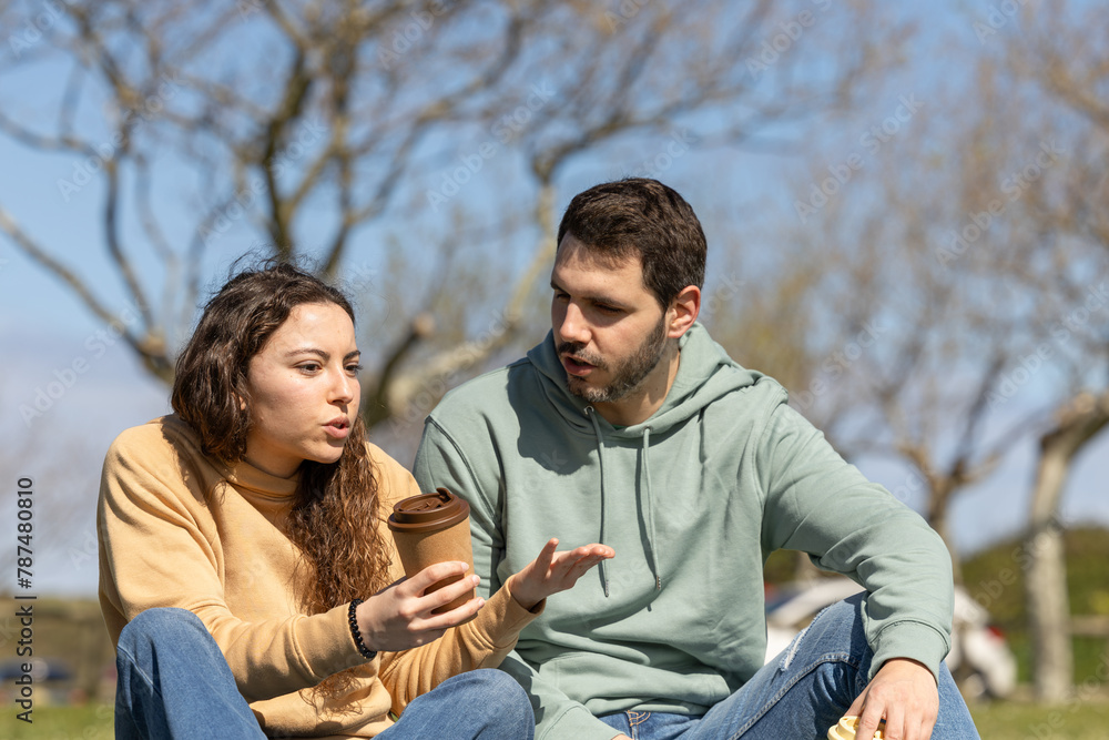 couple argue while talking in the park drinking coffee couple argue while talking in the park drinking coffee