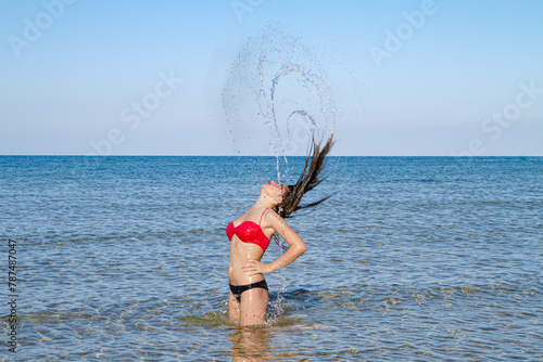 Smooth skin slender body happy stress free woman in bikini, having fun splashing sea water, breathing fresh air enjoying summer vacation freedom.