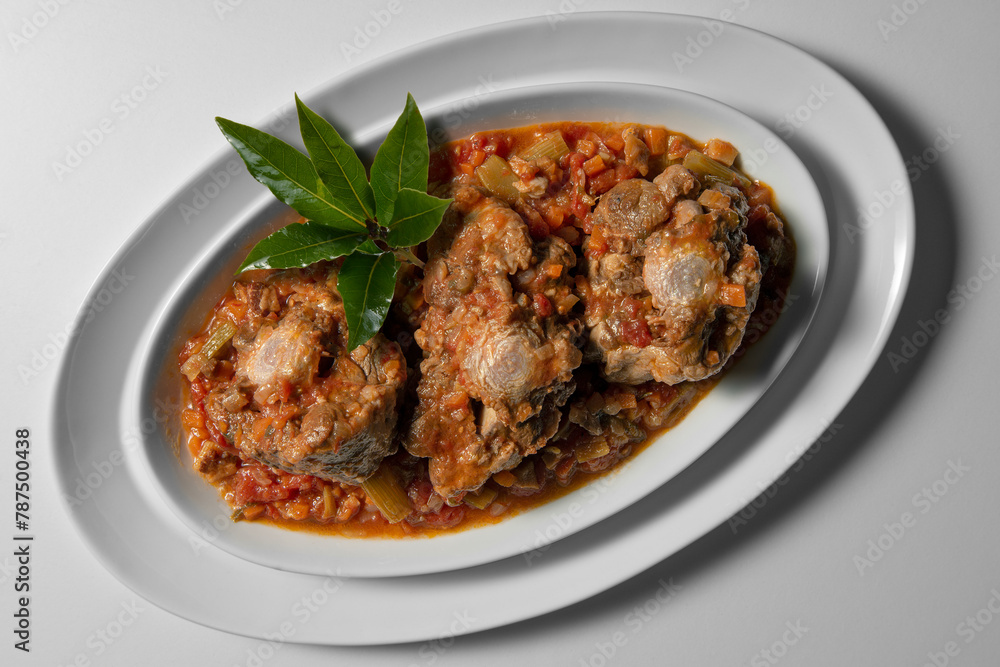 Isolated oval plate with a portion of oxtail stewed vaccinara Isolated oval plate with a portion of oxtail stewed vaccinara