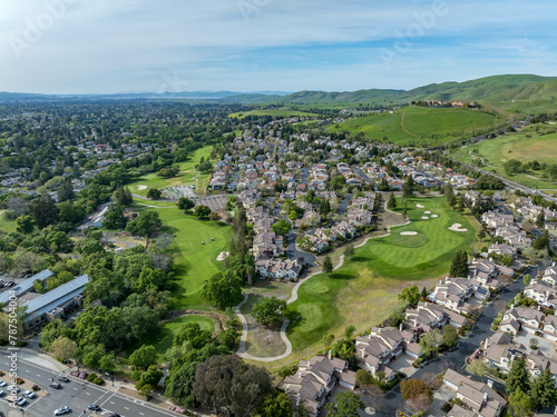 Drone photos over the Oakhurst neighborhood in Clayton, California with green hills, golf course and homes. photo