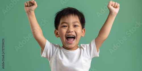 Southeast Asian boy laughing heartily, clad in a white shirt against a light mint green background, capturing the essence of joyful childhood.