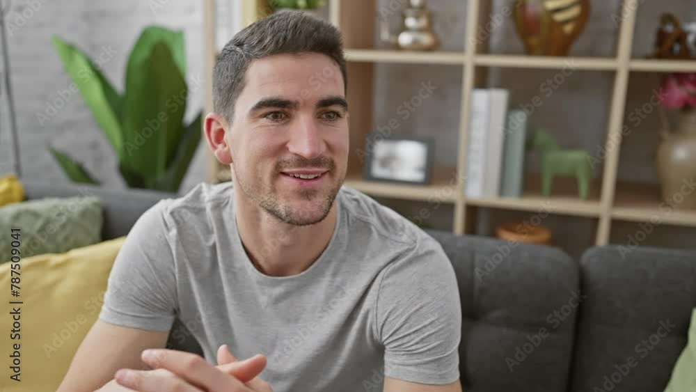 A handsome young man with a beard smiles in a modern living room interior. A handsome young man with a beard smiles in a modern living room interior.
