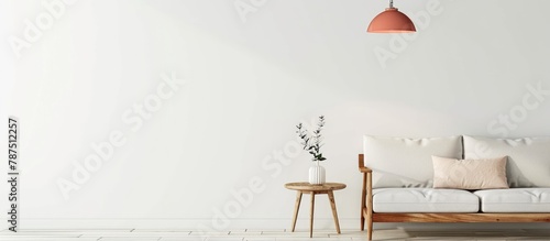 A vintage pink hanging lamp hangs over a wooden side table in a contemporary living room with a blank white wall and space for a sofa.