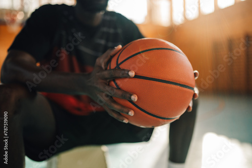 African american basketball player with a ball in his hands sitting on a bench