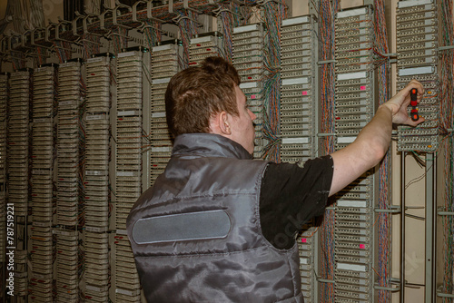 A man works in an old telephone PABX. Specialist will connect wires in an automated telephone station
