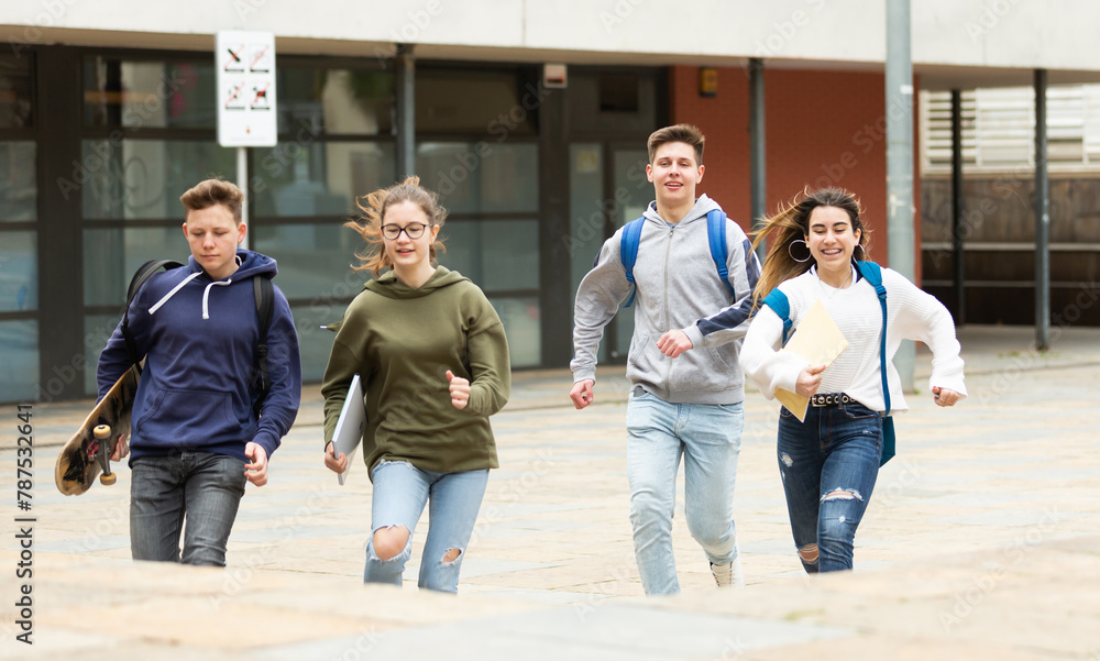 Fototapeta premium Group of cheerful glad students running outdoors in city street on good weather