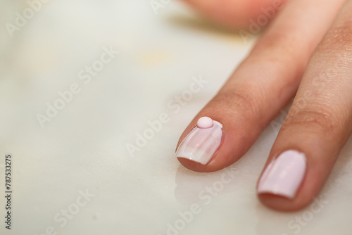 A drop of pink nail polish on her fingernail.