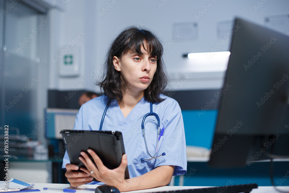Caucasian nurse in medical uniform analyzing prescriptions for patients on tablet and computer, working in a hospital office. Physician assistance comparing healthcare data on digital devices. Caucasian nurse in medical uniform analyzing prescriptions for patients on tablet and computer, working in a hospital office. Physician assistance comparing healthcare data on digital devices.